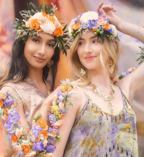 two women with flowers on arms and head